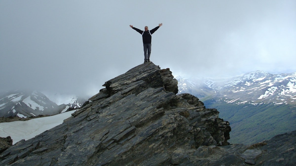 a man standing on top of a mountain with his arms wide open